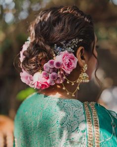 a woman with flowers in her hair is wearing a green sari and gold jewelry