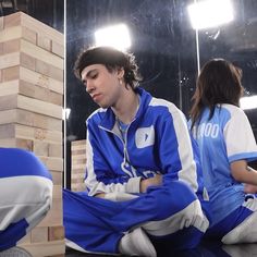 a young man sitting on the ground next to a pile of blocks in front of a mirror