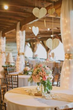 a white table topped with a vase filled with flowers and hearts hanging from the ceiling