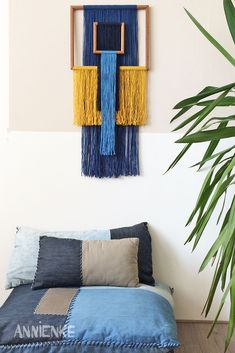 a bed with blue and yellow pillows on top of it next to a potted plant