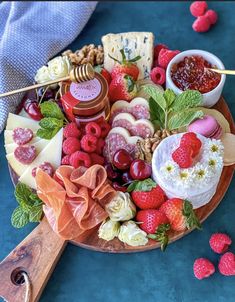 a platter filled with cheese, fruit and crackers on a blue table cloth