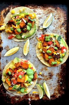 three tortillas on a baking sheet with avocado, corn and tomatoes