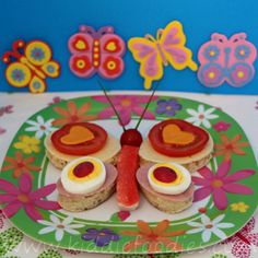 a plate topped with sandwiches covered in cheese and toppings next to a butterfly decoration