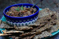 a blue and white bowl filled with food next to crackers