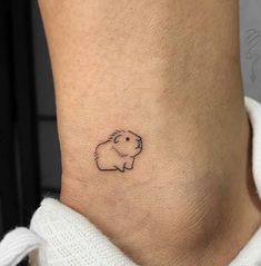 a small tattoo on the ankle of a woman's leg shows a guinea pig