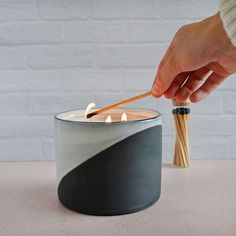 hand holding a match to light a 3 wick ceramic candle with matches in the background Cozy Aesthetic, Cozy Room Decor