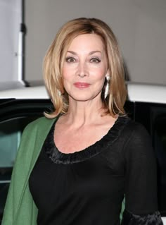 a woman standing in front of a white car with her hand on her hip and smiling at the camera