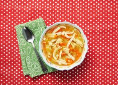 a bowl of chicken noodle soup on a red and white polka dot tablecloth