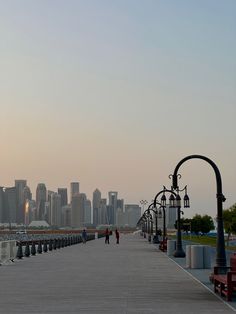 people are walking along the boardwalk in front of some tall buildings