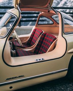 an old car with the door open and plaid seat covers on it's seats