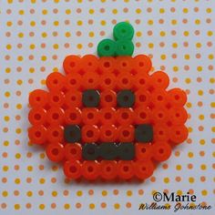 an orange beaded brooch with a pumpkin on it