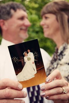 a man and woman holding up an old photo in front of their wedding day guests