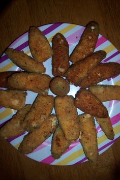 some fried food is on a plate on a wooden table with colorful stripes and lines