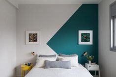 a bed with white sheets and pillows in a room painted teal green and grey