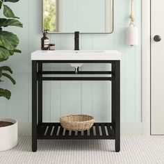 a white sink sitting under a bathroom mirror next to a potted plant and door