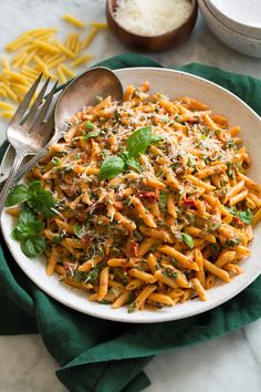 a white bowl filled with pasta and parmesan cheese on top of a green napkin