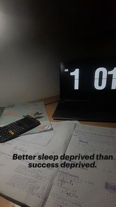 an alarm clock sitting on top of a desk next to a book and calculator