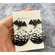 a pair of black and white earrings with bats on them in front of a card