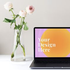 an open laptop computer sitting on top of a desk next to a vase with flowers