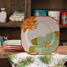 a stack of plates sitting on top of a wooden table next to other dishes and cups