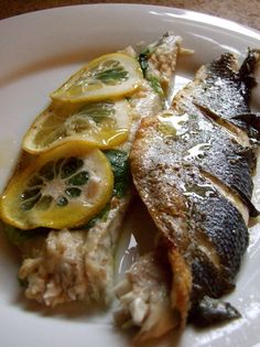 a plate with fish, lemons and rice on it