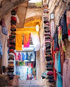 an alley way with clothes hanging from the ceiling and other items on display in front of it