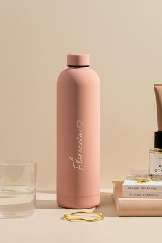 a pink water bottle sitting on top of a table next to some skin care products