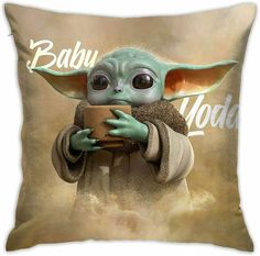 a baby yoda holding a coffee cup on top of a brown pillow with the words baby yoda printed on it