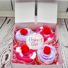 three cupcakes in a box with pink and purple frosting