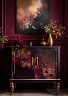 a painting on the wall next to a cabinet with flowers and vases in it