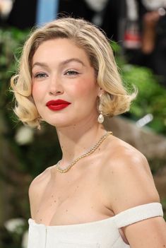 a woman with blonde hair wearing a white dress and red lipstick is posing for the camera