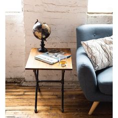 a blue chair with a book on it next to a small table and a lamp