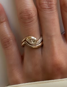 a woman's hand with a gold ring on top of it and a diamond in the middle