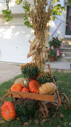 a wheelbarrow filled with pumpkins and gourds in front of a house