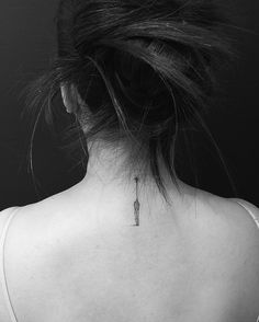 the back of a woman's neck with a small tattoo on it