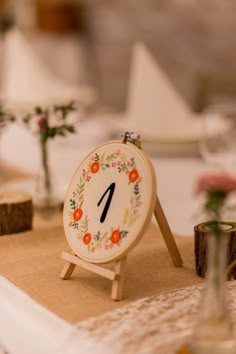 a small clock sitting on top of a table next to some flowers and vases