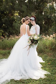 two brides standing in the grass looking at each other