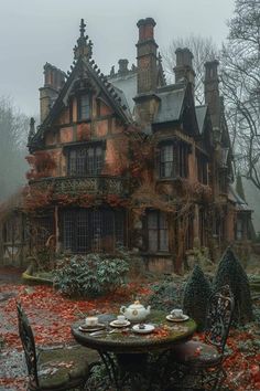 a table and chairs in front of an old house with autumn leaves on the ground