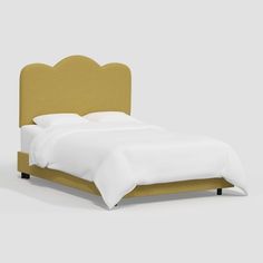 an upholstered bed with white linens and gold headboard is shown against a gray background