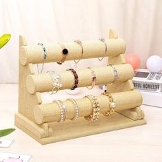 a wooden display rack with rings and bracelets on it next to a vase filled with flowers