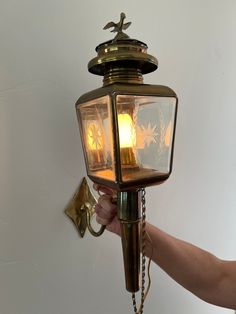 a person holding onto a light that is attached to a wall