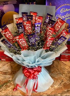 a bouquet of chocolates and candy wrapped in red ribbon on top of a table