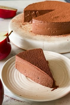 there is a piece of chocolate cake on the plate and an apple next to it