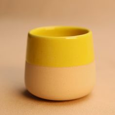 a yellow and white cup sitting on top of a table