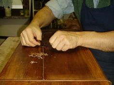 a man in an apron is cutting wood with a knife