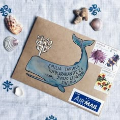 an envelope with a whale on it surrounded by sea shells and seashells is shown