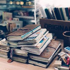 a pile of books sitting on top of a wooden table next to a cup and other items