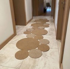 a long hallway with several round rugs on the floor next to an open door