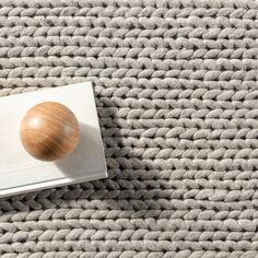 an overhead view of a book with a wooden object on it sitting on a knitted surface