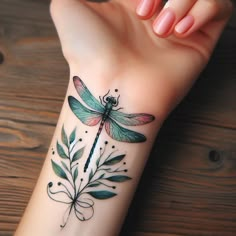 a woman's arm with a dragonfly tattoo on it and leaves around the wrist